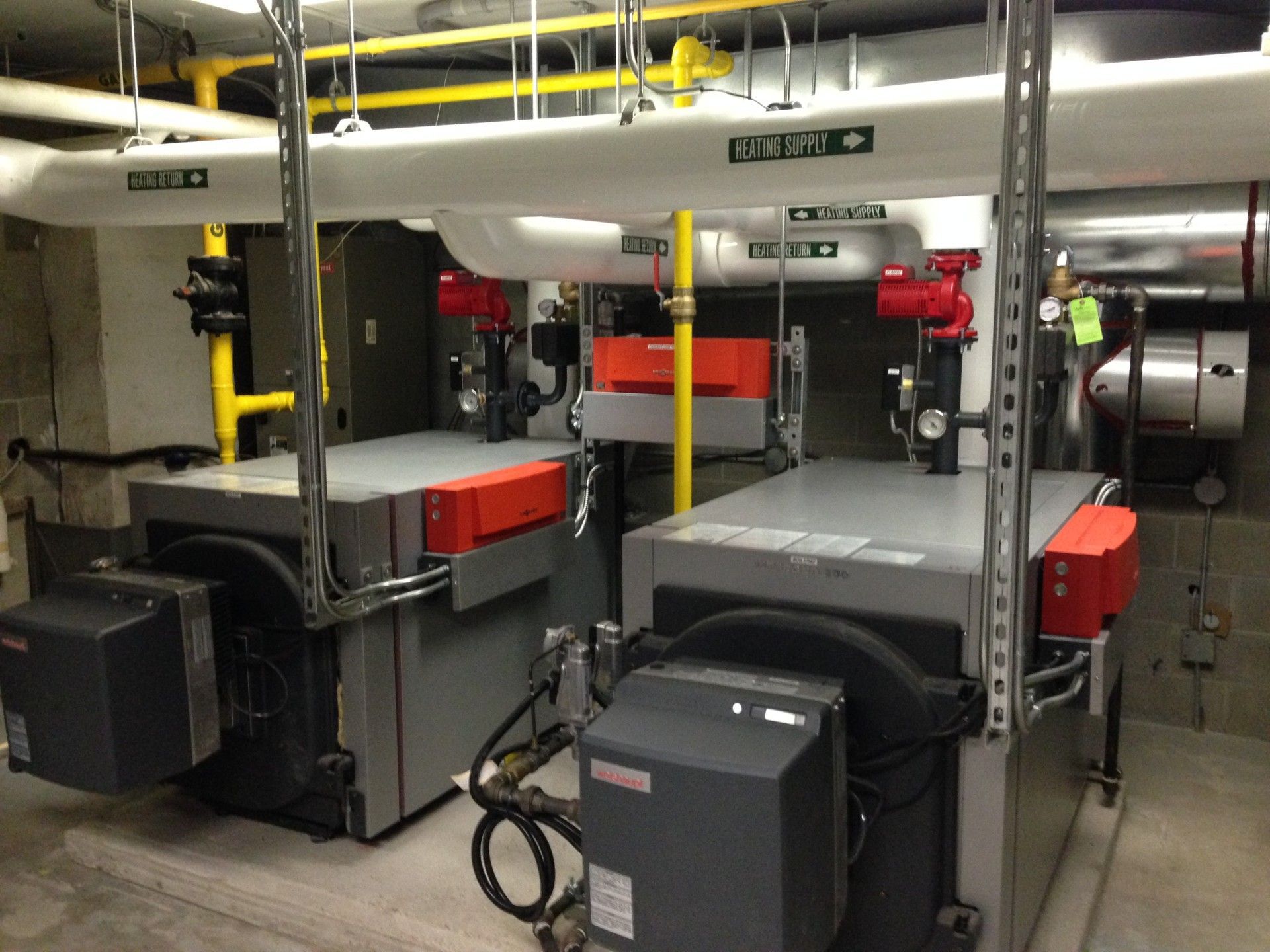Two industrial boilers with piping in a mechanical room.