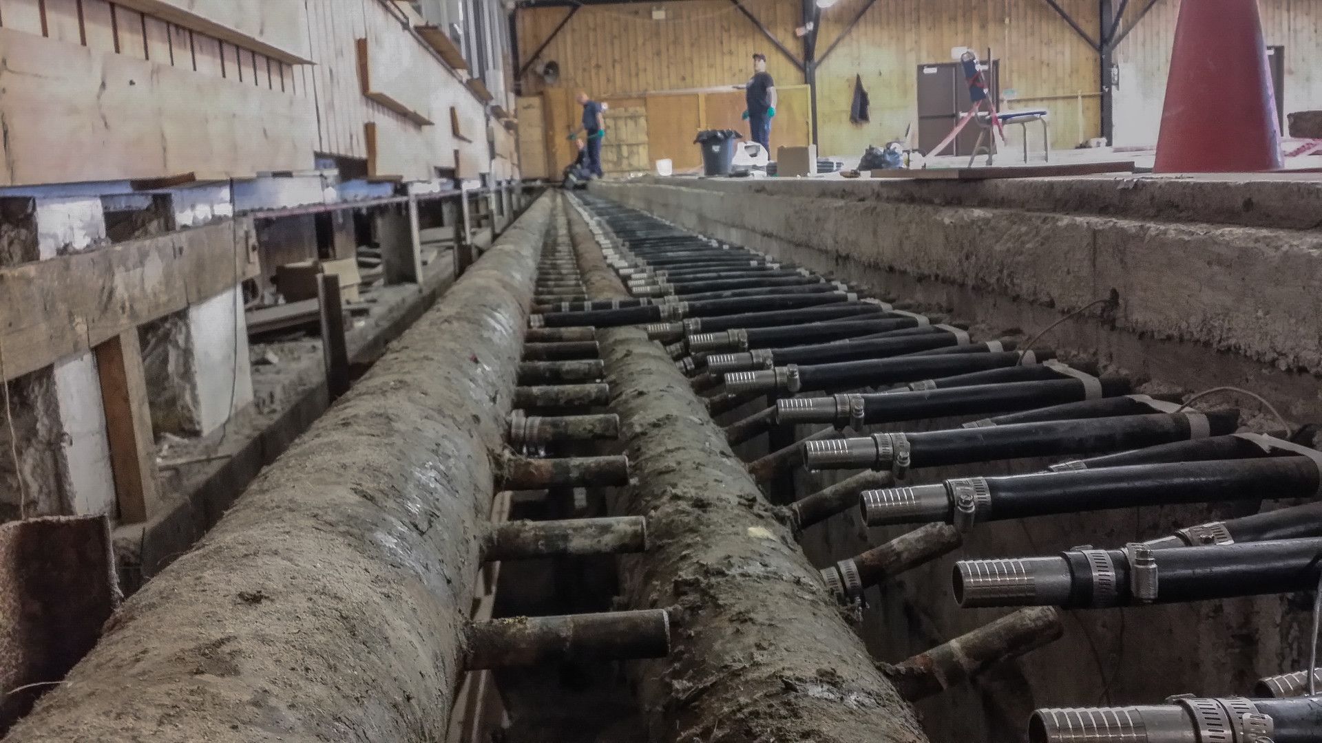 Concrete construction with cables and pipes in a trench, likely a building foundation.