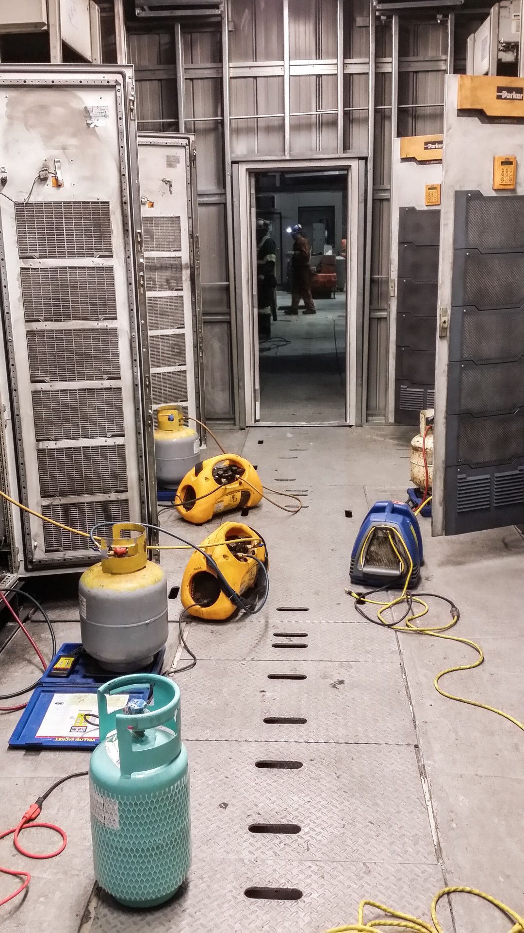 An industrial-looking hallway with equipment, tanks, and a doorway.