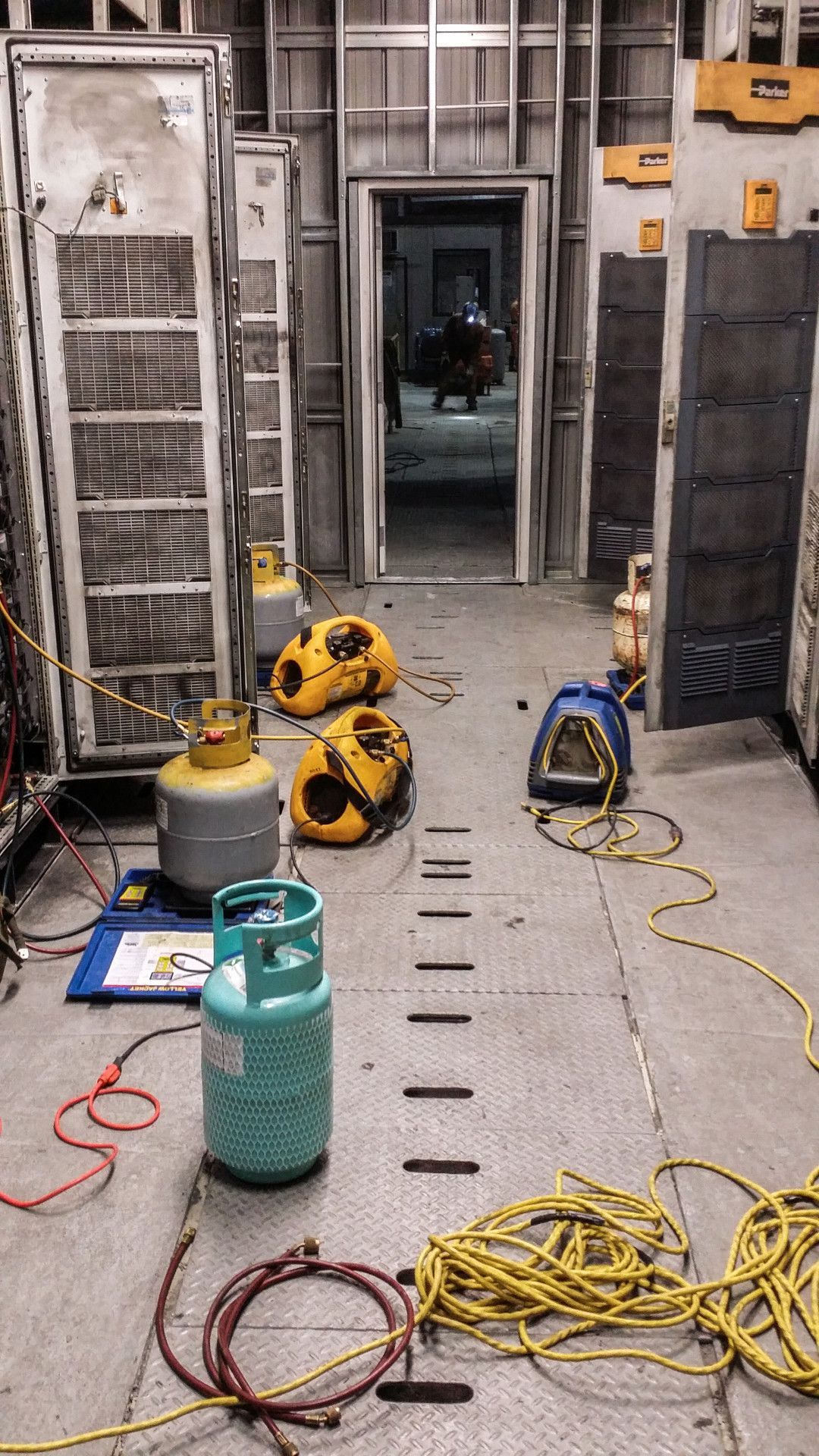 A narrow industrial hallway filled with equipment, cylinders, and tools.