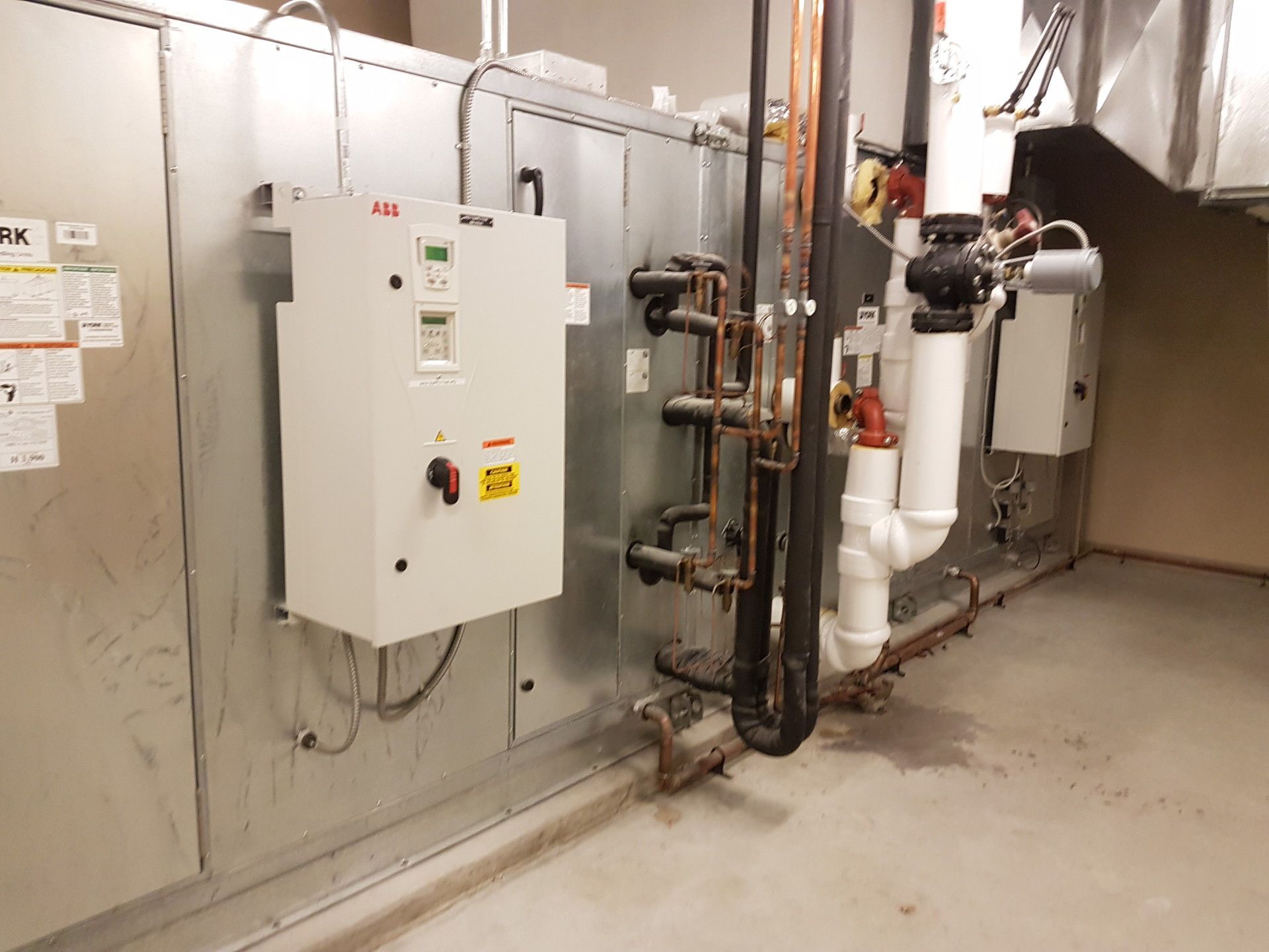 HVAC system with electrical panel, pipes, and ducts in a utility room.