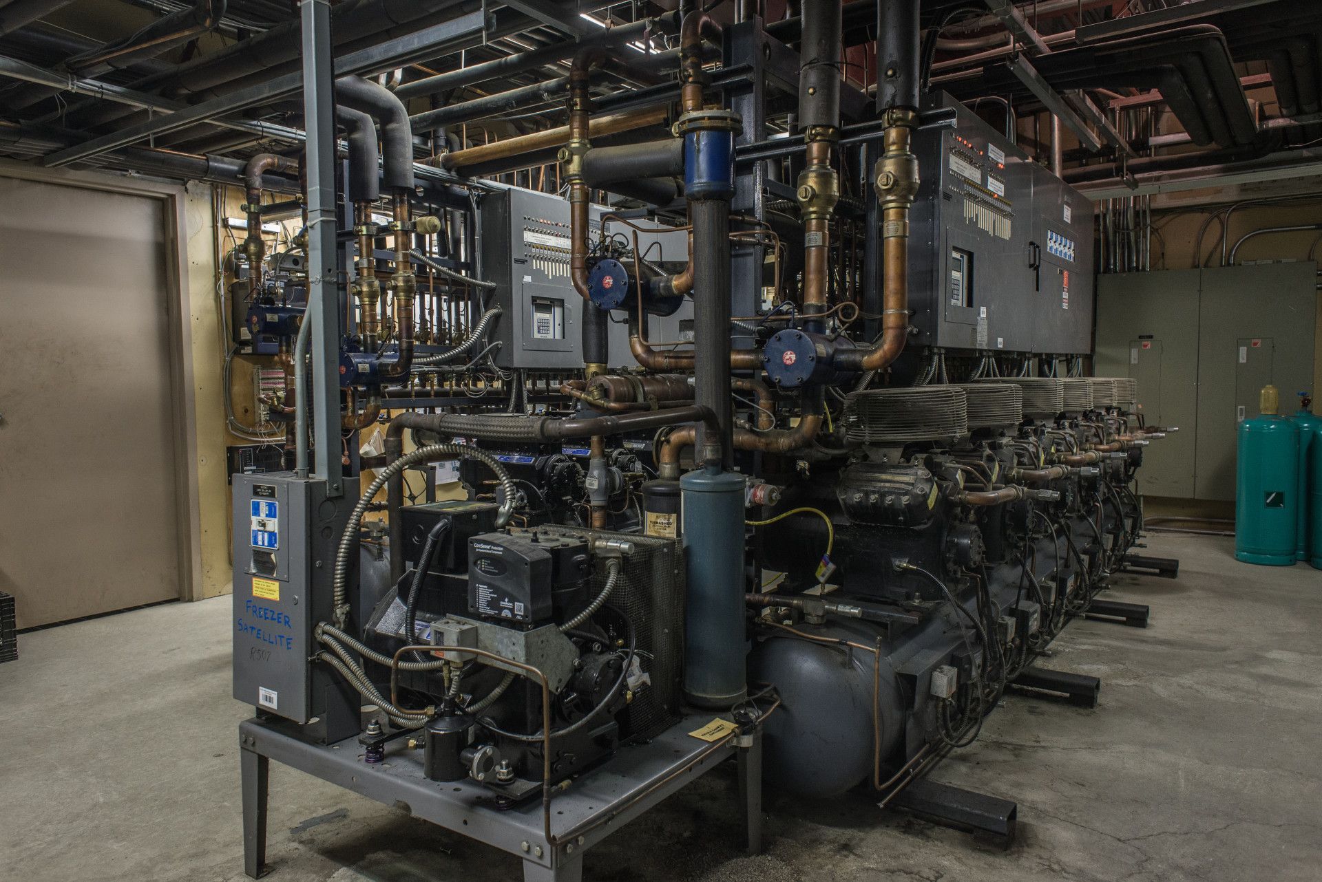 Industrial equipment in a utility room, with pipes, valves, and a large machine.