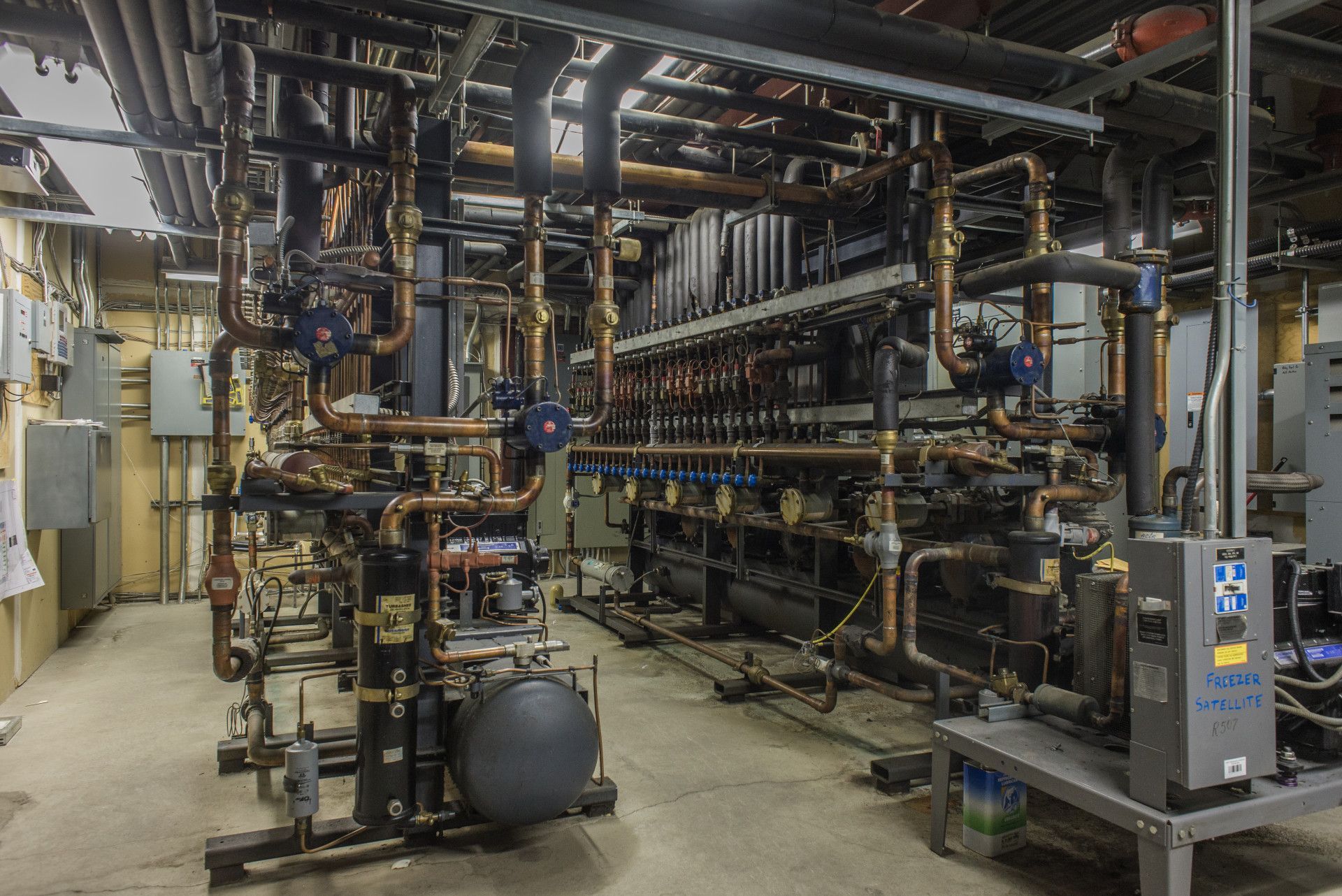 Complex industrial machinery with numerous pipes and valves in a utility room.