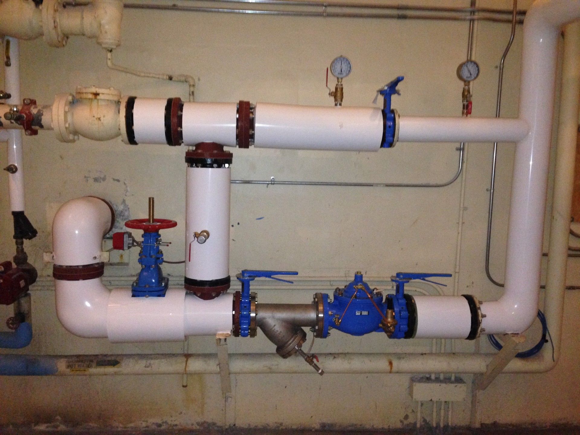 White pipes with blue valves in an industrial setting, likely for water or gas.