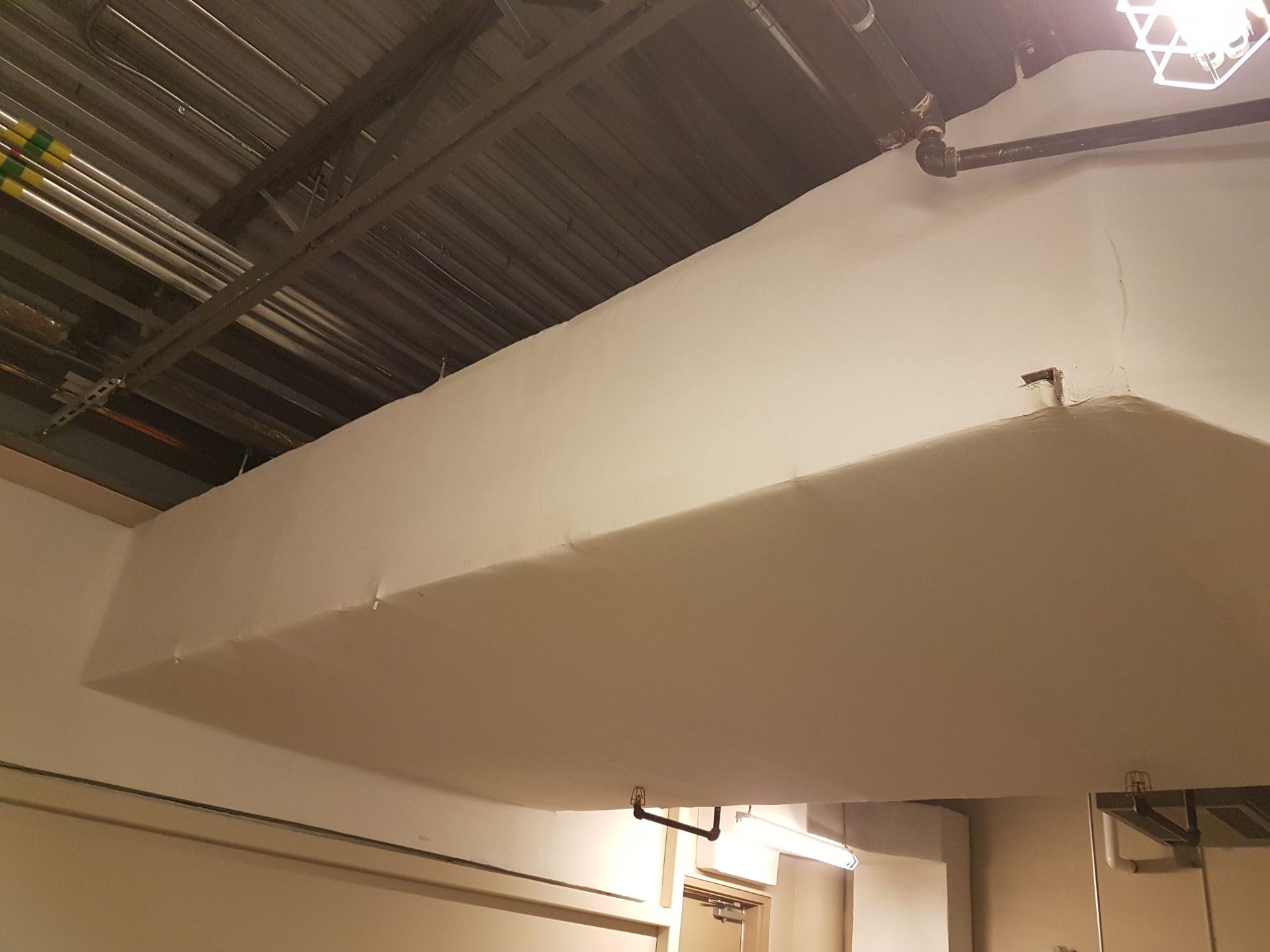 White soffit suspended from ceiling, concealing infrastructure; industrial setting.