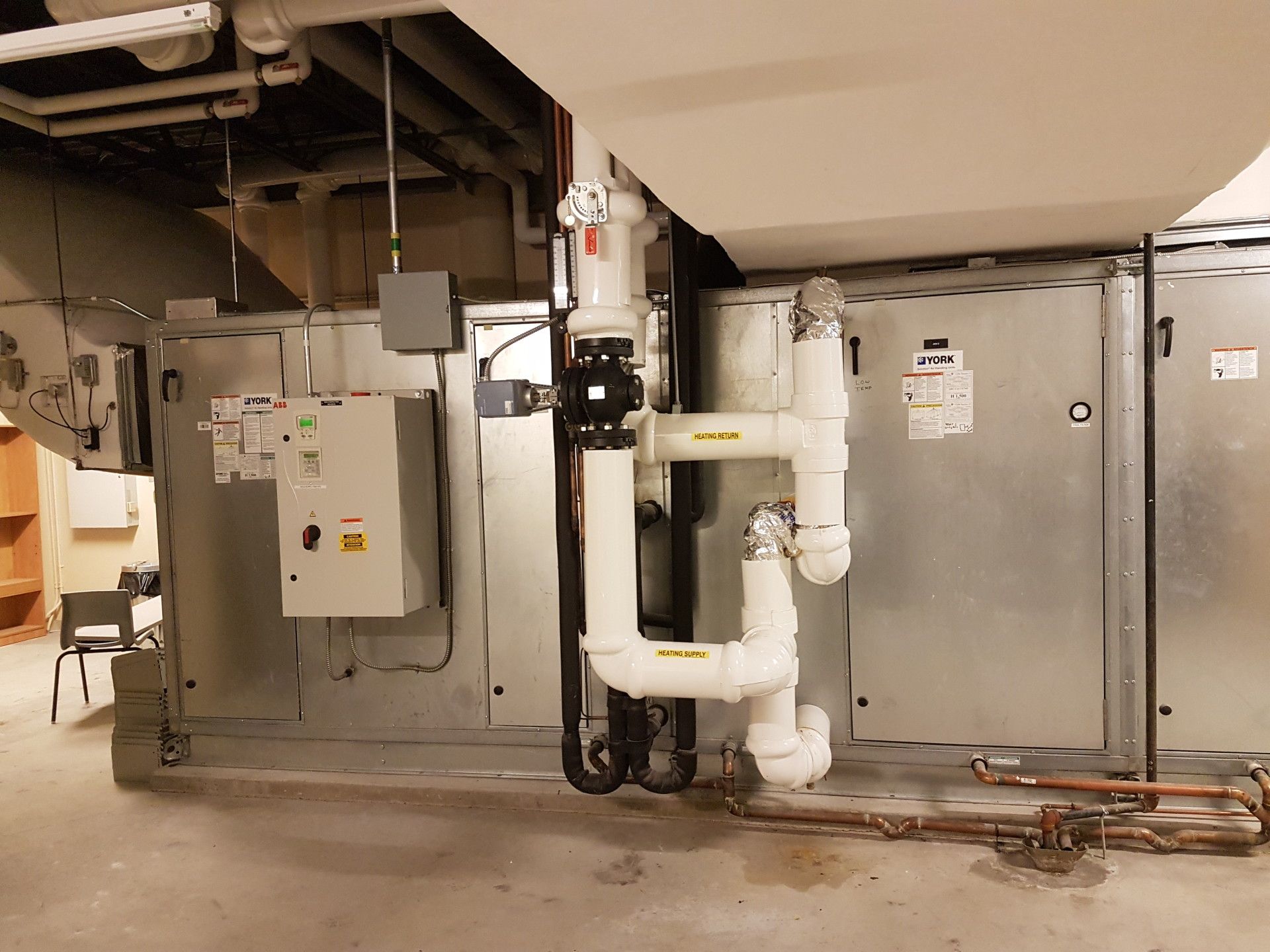 HVAC system with white insulated pipes, electrical boxes, and copper piping in a basement setting.