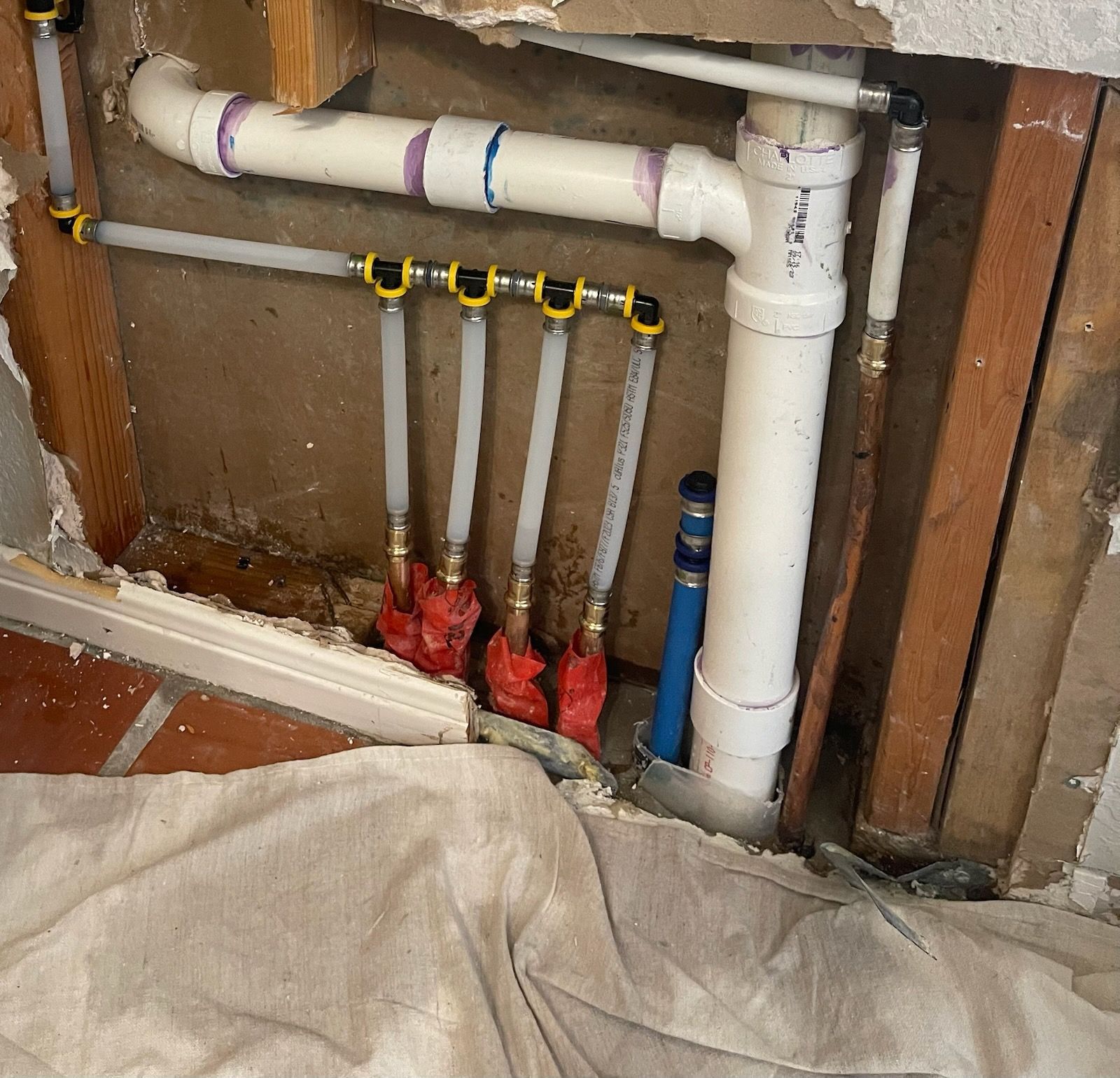 Rusty pipes joined by black fittings buried in dark soil near grass.