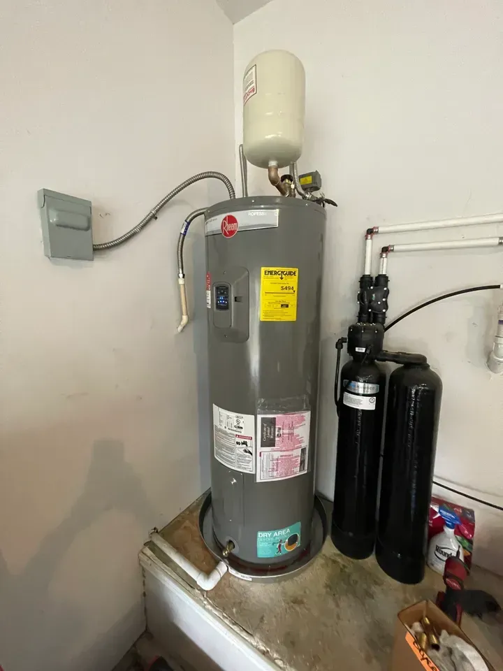 A tall gray water heater with a white expansion tank, and two black tanks standing next to it.