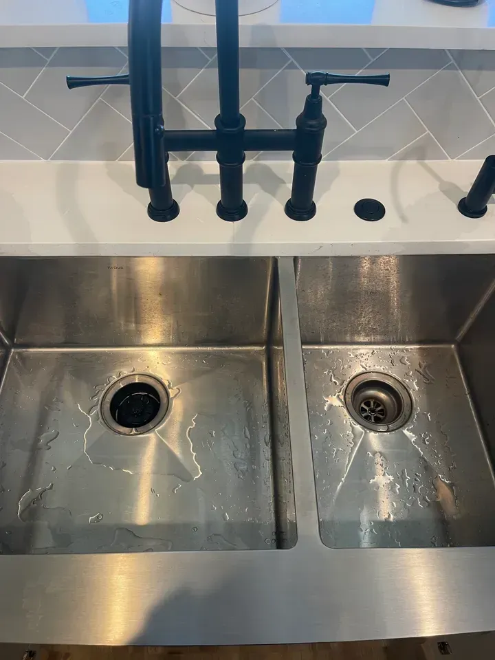 Stainless steel double kitchen sink with black faucet and countertop.