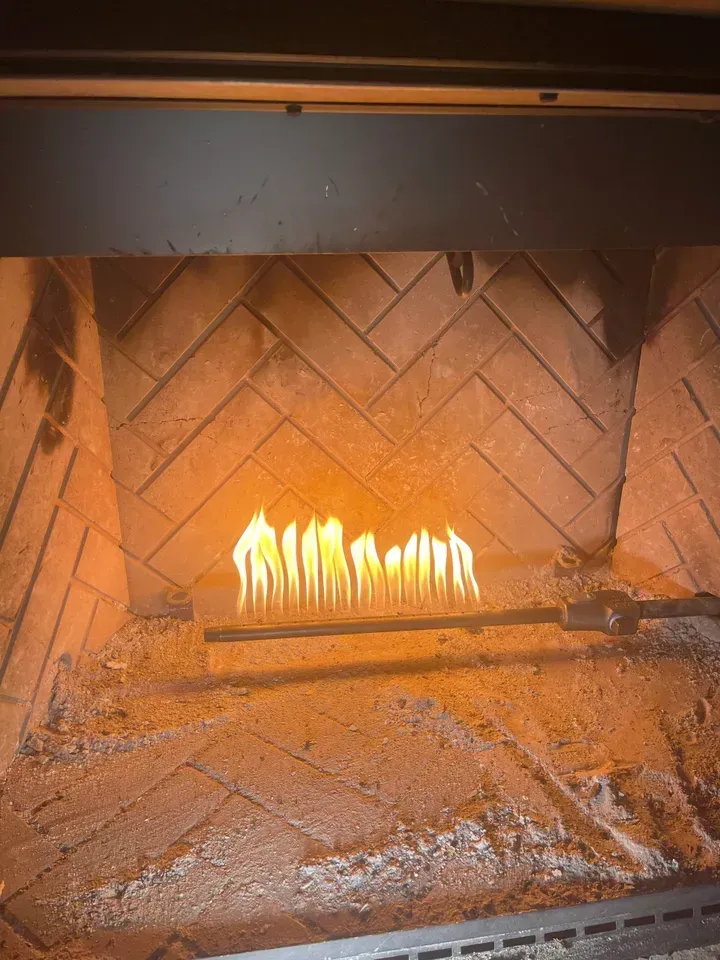 Flames burning from a gas fireplace inside a brick-lined fireplace.
