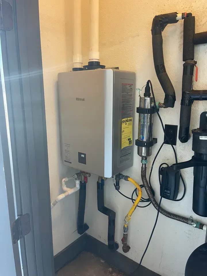 Tankless water heater and plumbing in a corner. Pipes, gas line, and UV filter are visible.
