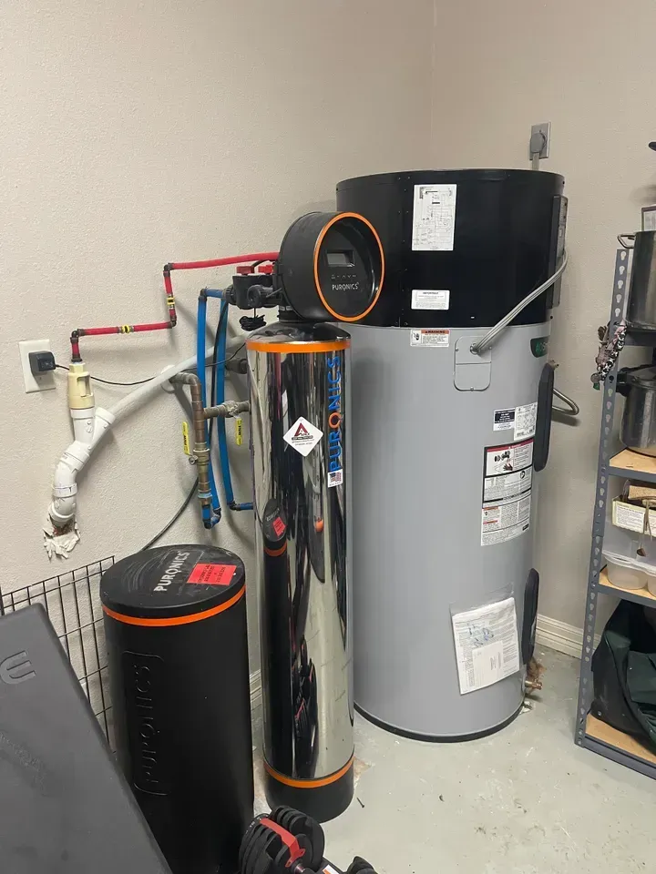 Water heater and filtration system in a utility room.  Gray, black and chrome tanks and pipes.