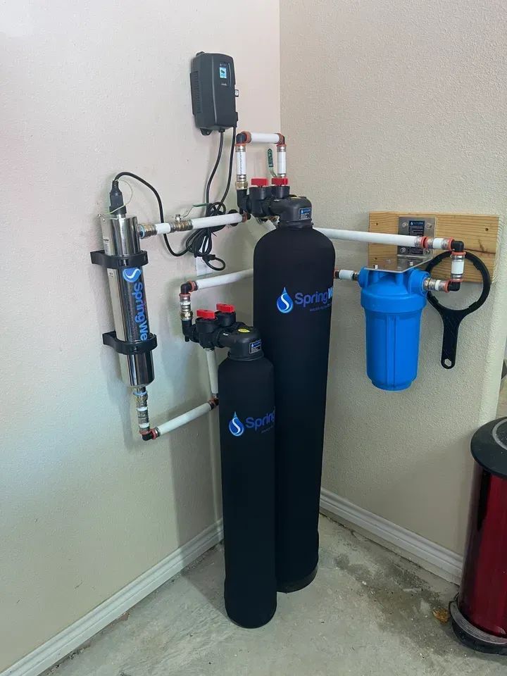 Water filtration system mounted on a wall. Includes tanks, filters, and UV light sterilizer.