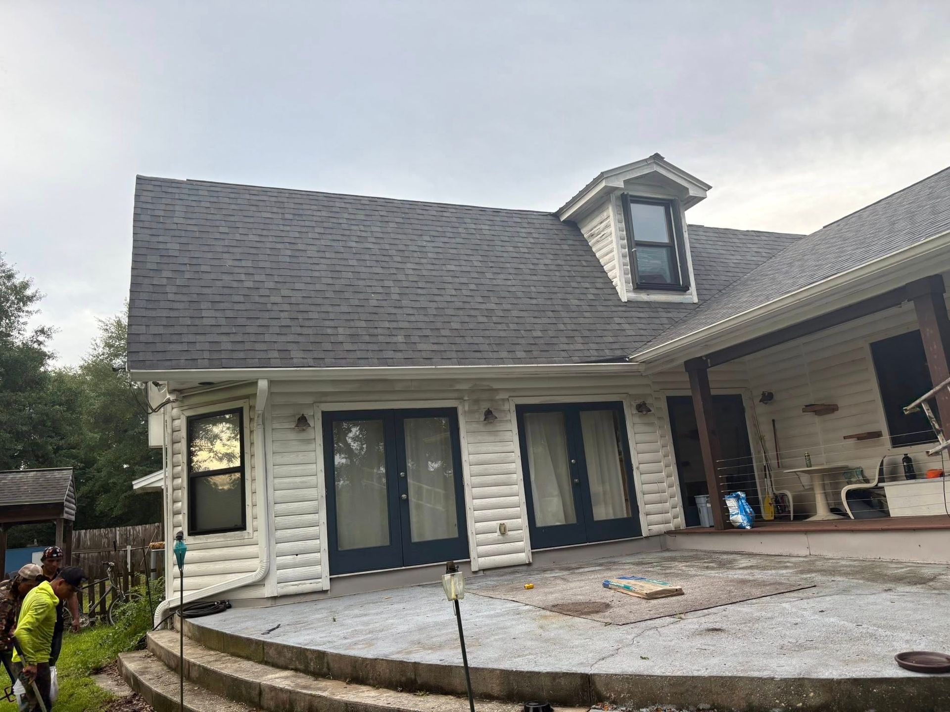 House with a gray roof and white siding, featuring French doors and a small dormer window.