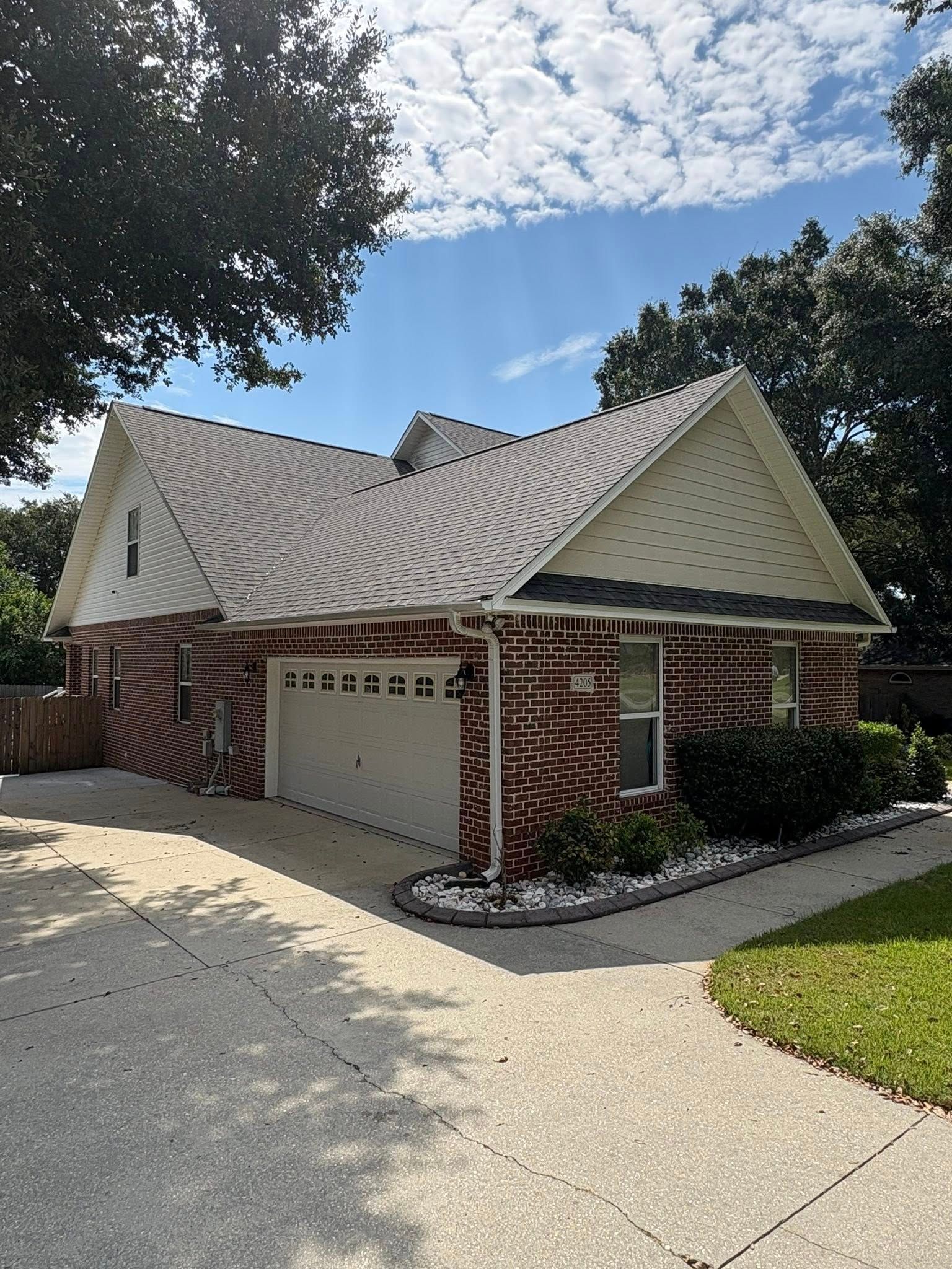 Red brick house with white garage door and roof, driveway, and blue sky.