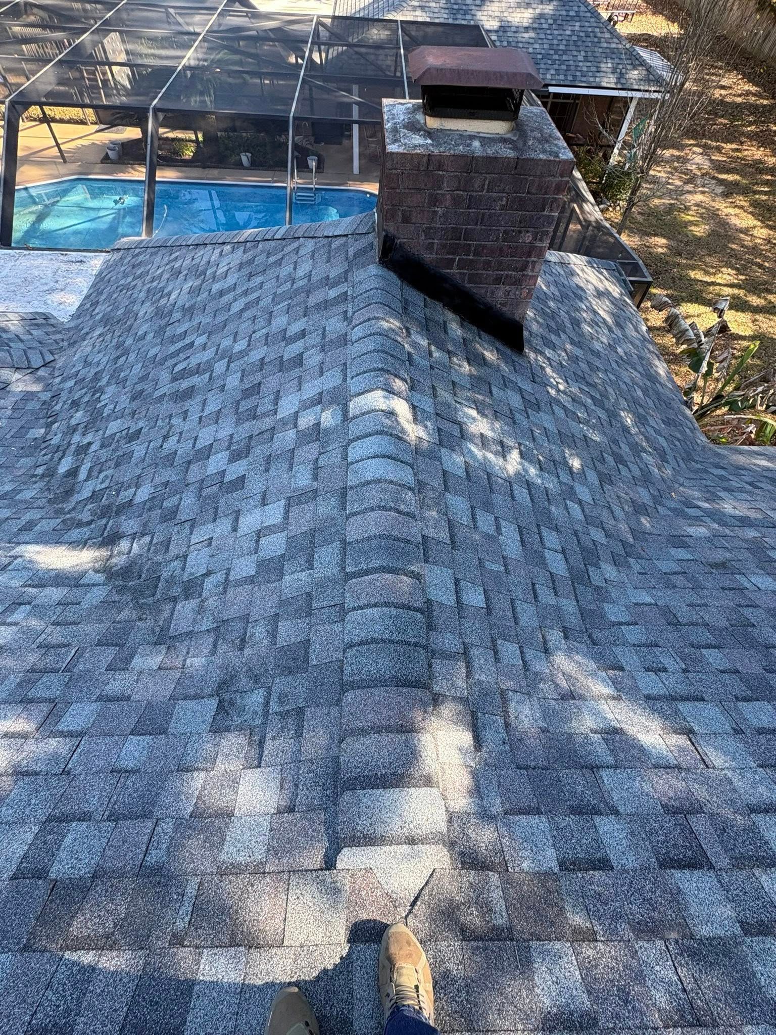 View from roof with gray shingles and a brick chimney, overlooking a pool.