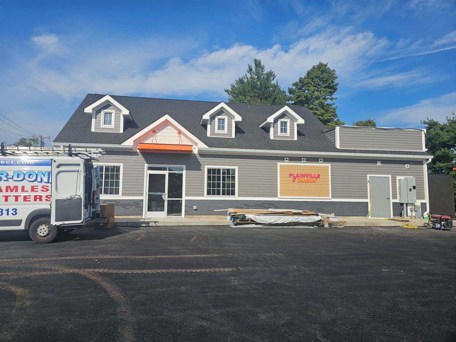 A construction worker is sitting on the roof of a building looking at his phone.