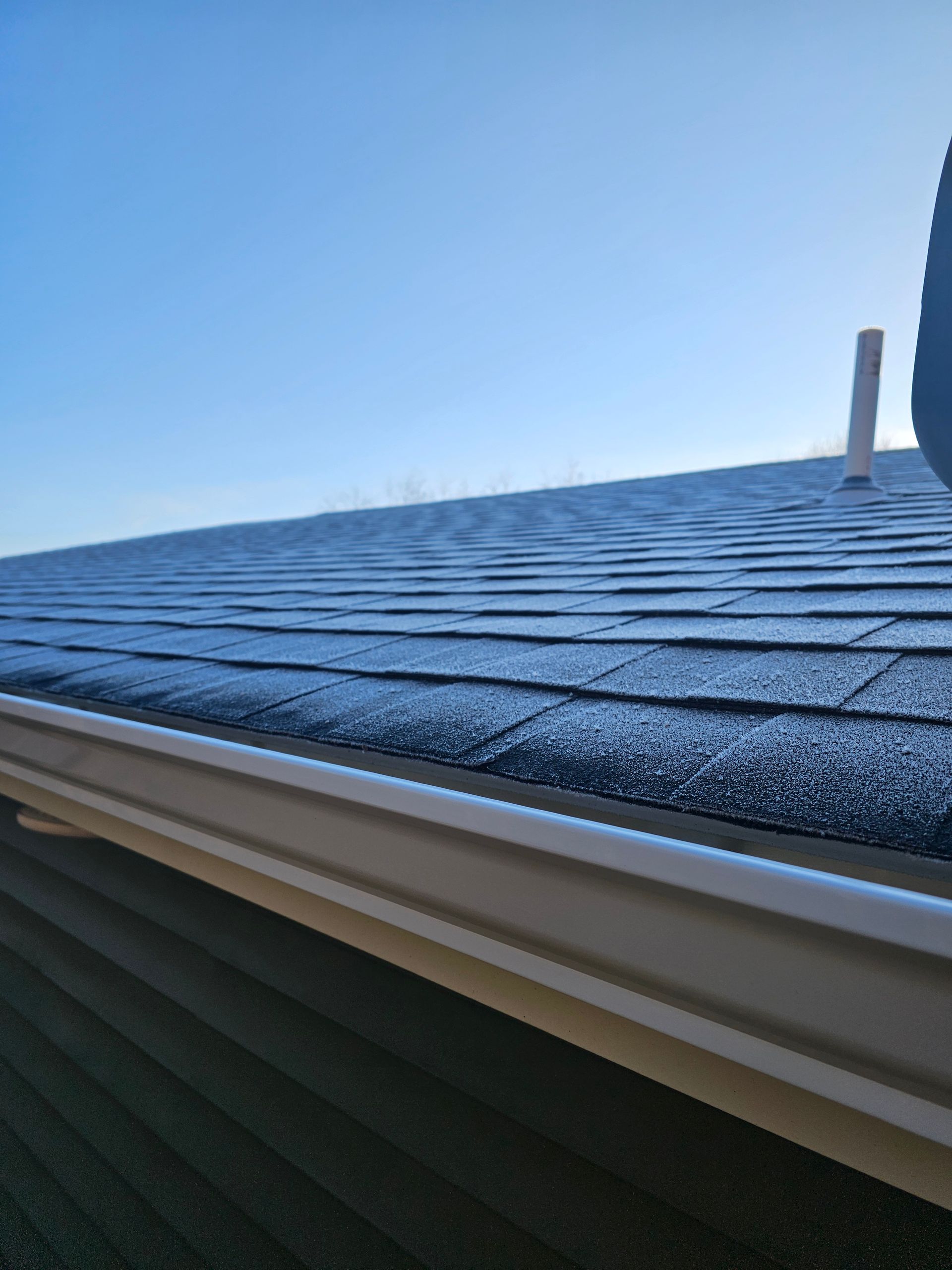 A close up of the roof of a house with a blue sky in the background.