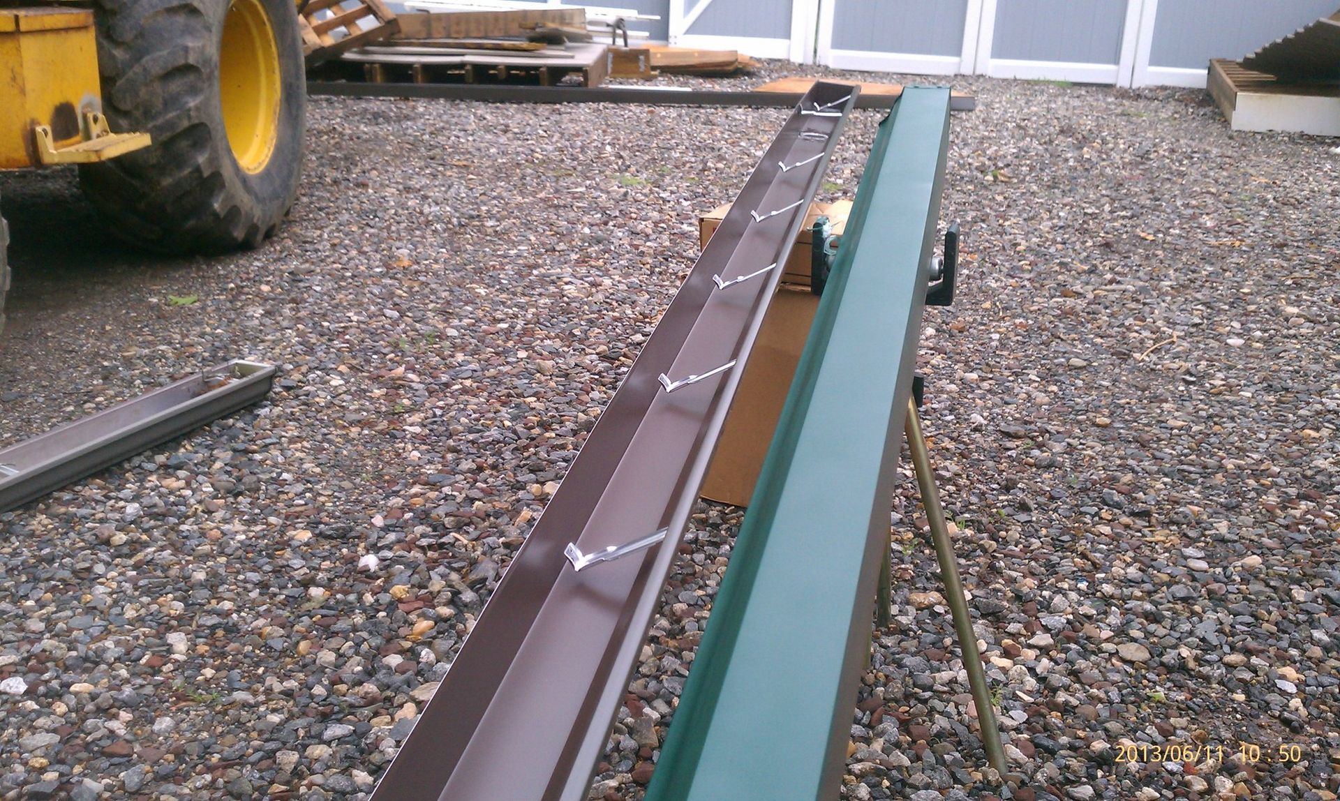 A green and brown piece of metal is sitting on a gravel ground