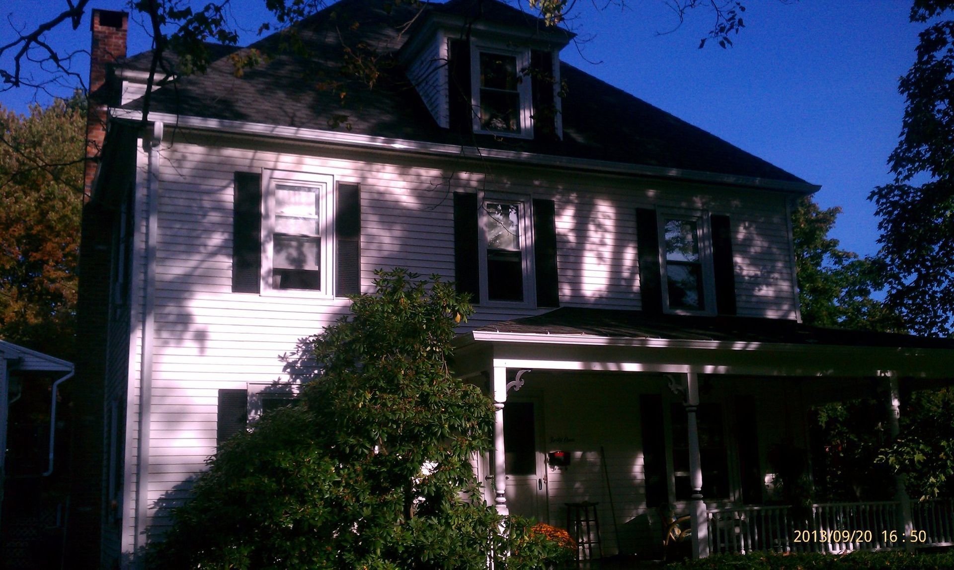 A white house with black shutters and a porch
