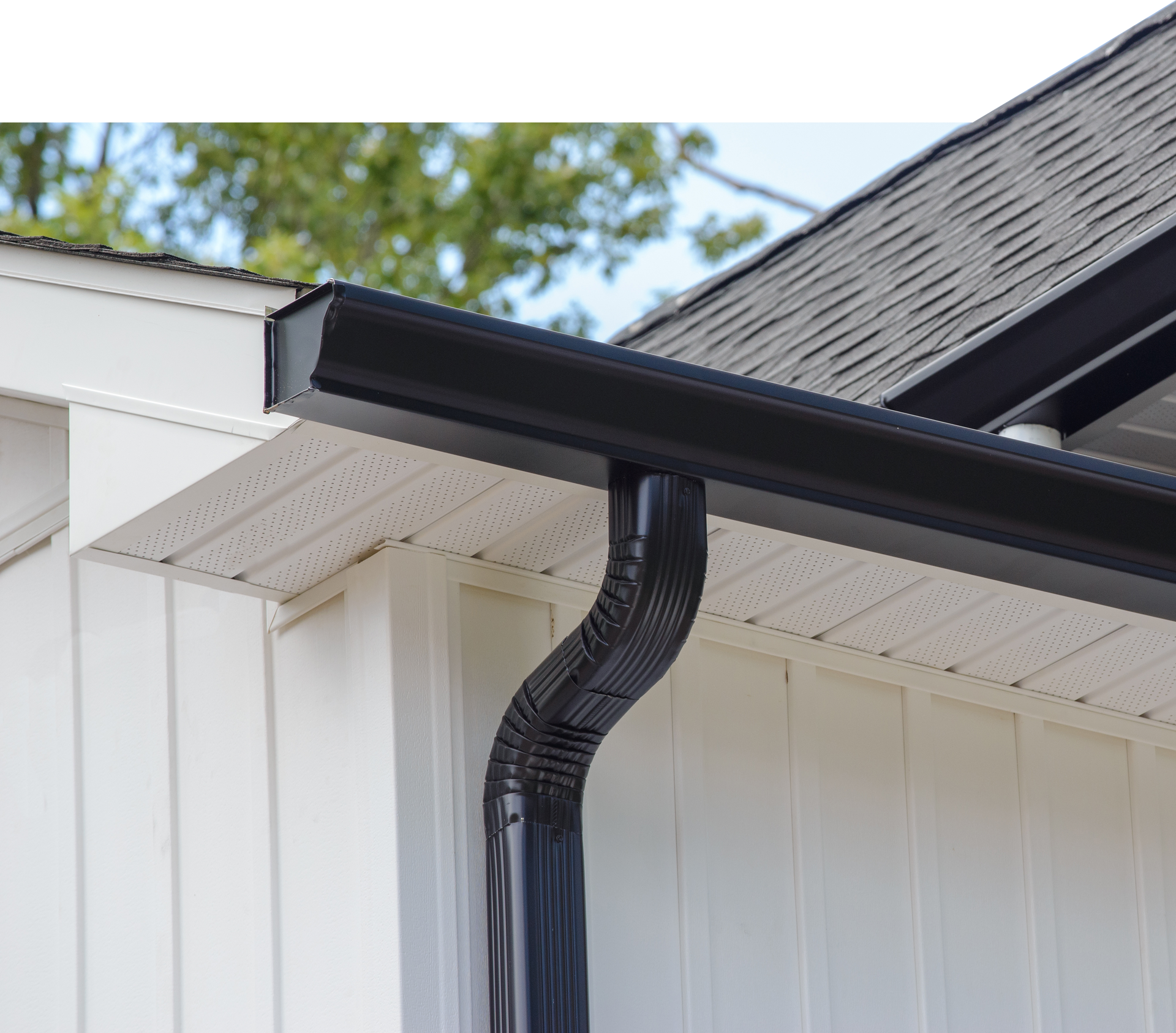 A black gutter is on the side of a white house.