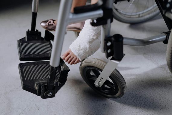 A person with a cast on their foot is sitting in a wheelchair.