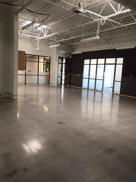 A large empty room with a concrete floor and a lot of windows.