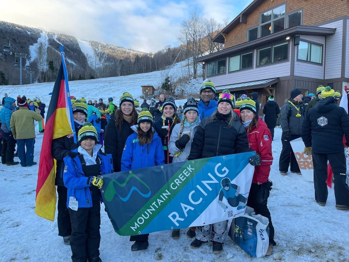Group of people with flags and banner, in front of a building in a snowy area.