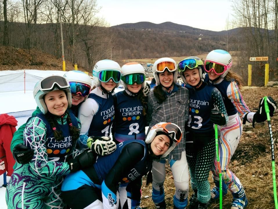 Group of skiers in colorful gear smiling at a ski slope.