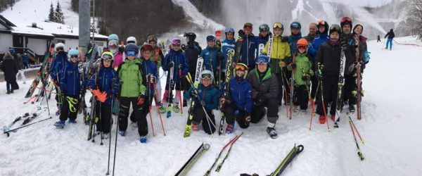 A group of skiers in winter gear posing for a photo on a snowy slope.
