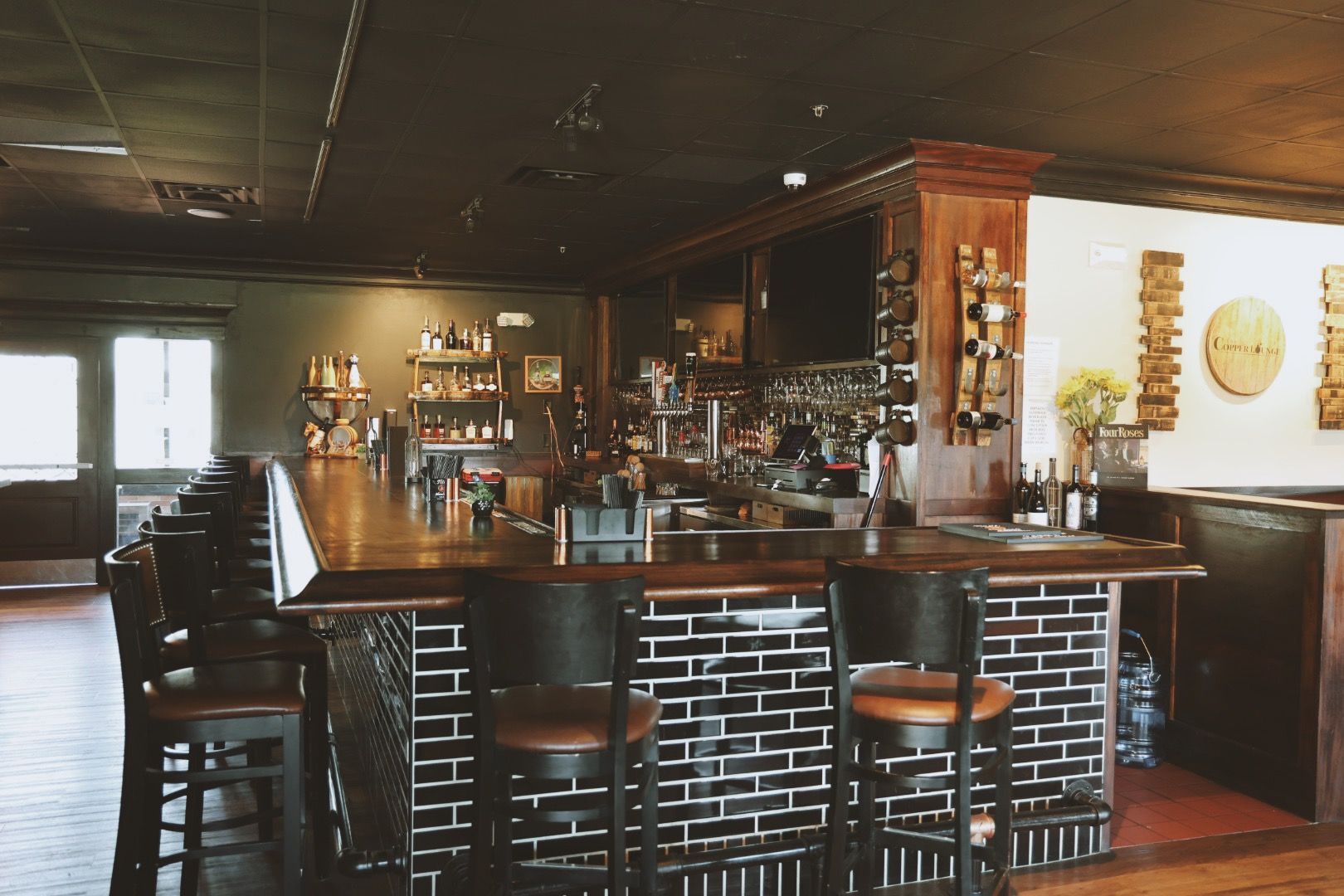 A restaurant with a long bar and a lot of chairs.
