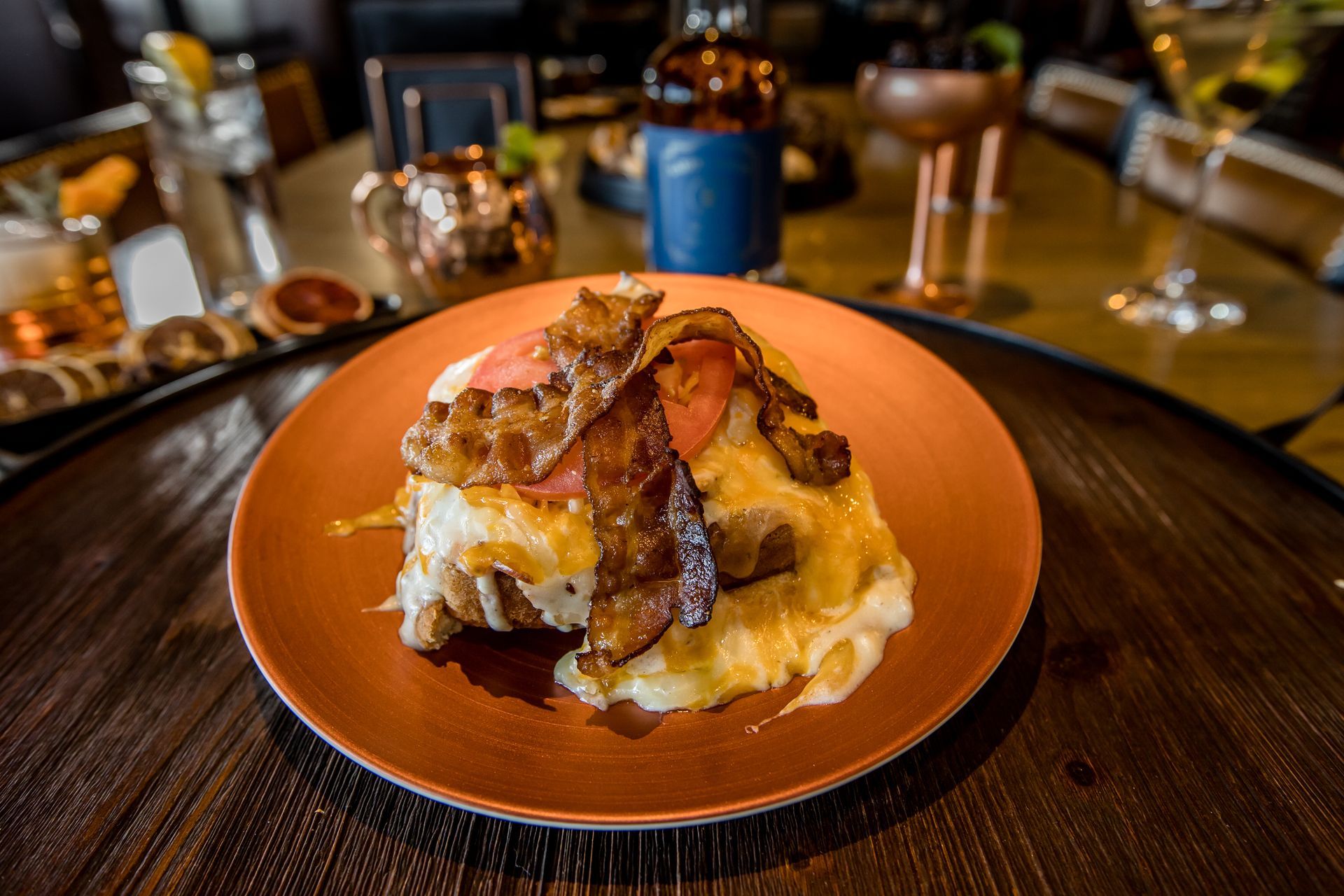 A plate of food with bacon and mashed potatoes on a wooden table.