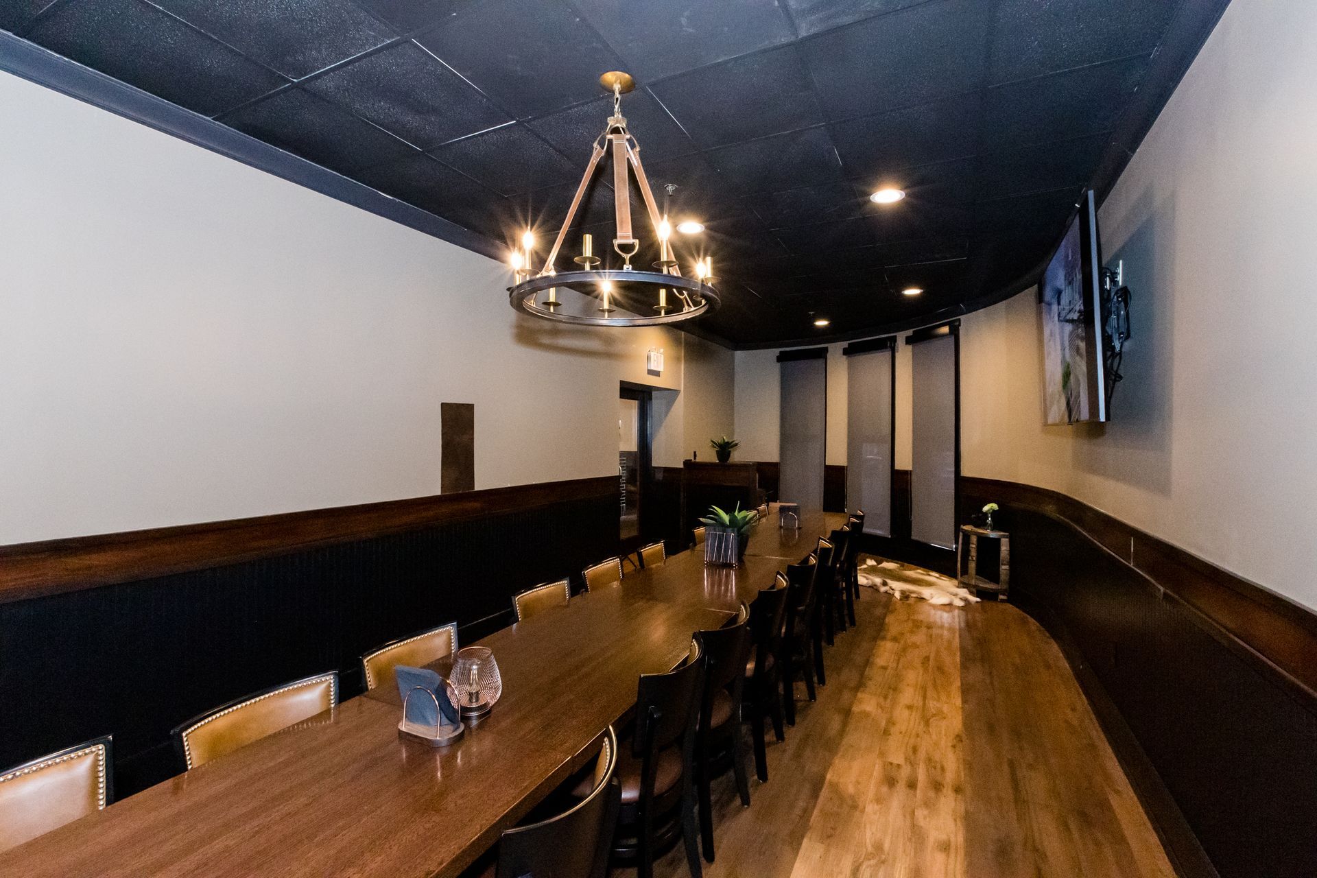 A long table and chairs in a room with a chandelier hanging from the ceiling.