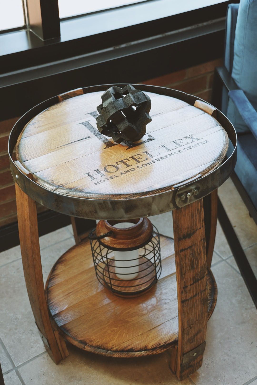 A wooden table made out of a wine barrel with a lamp on it.