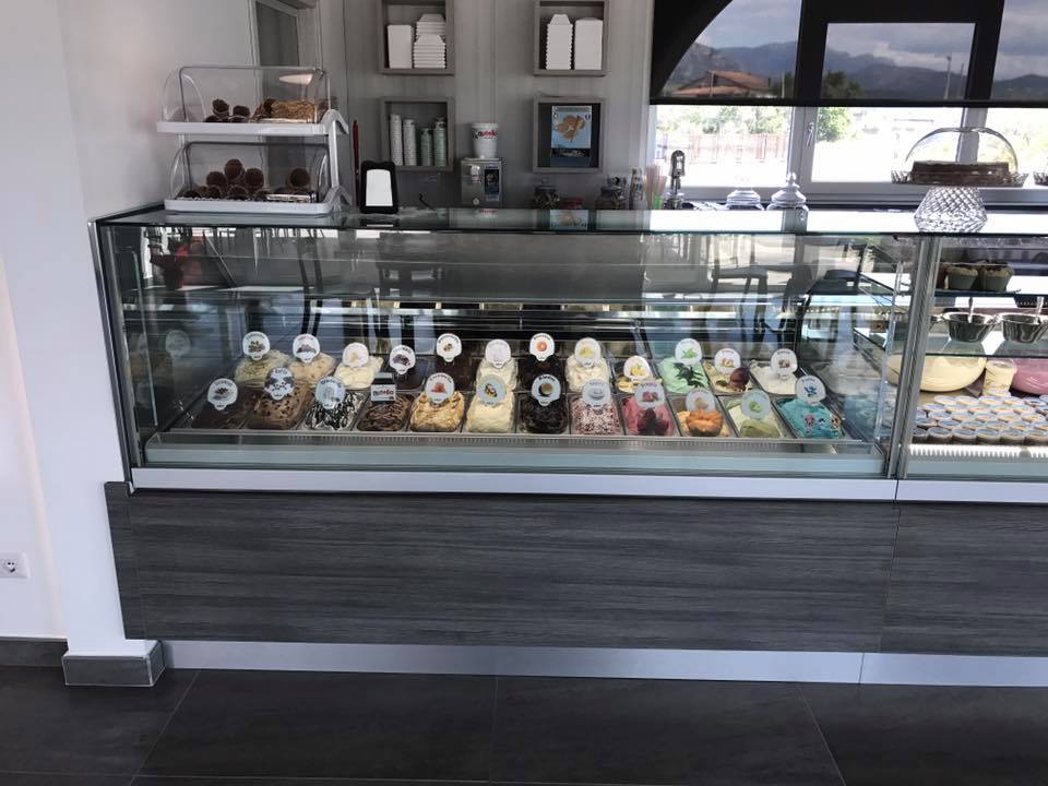 Vetrina di gelati piena di vari gusti in un negozio ben illuminato.