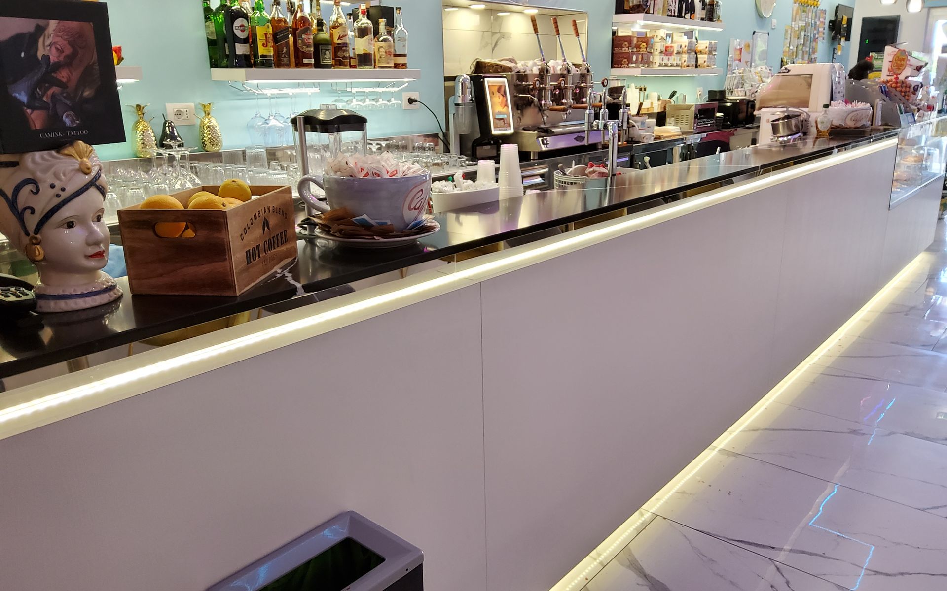 Un bancone da bar ben illuminato con vetrina, limoni e area bar.