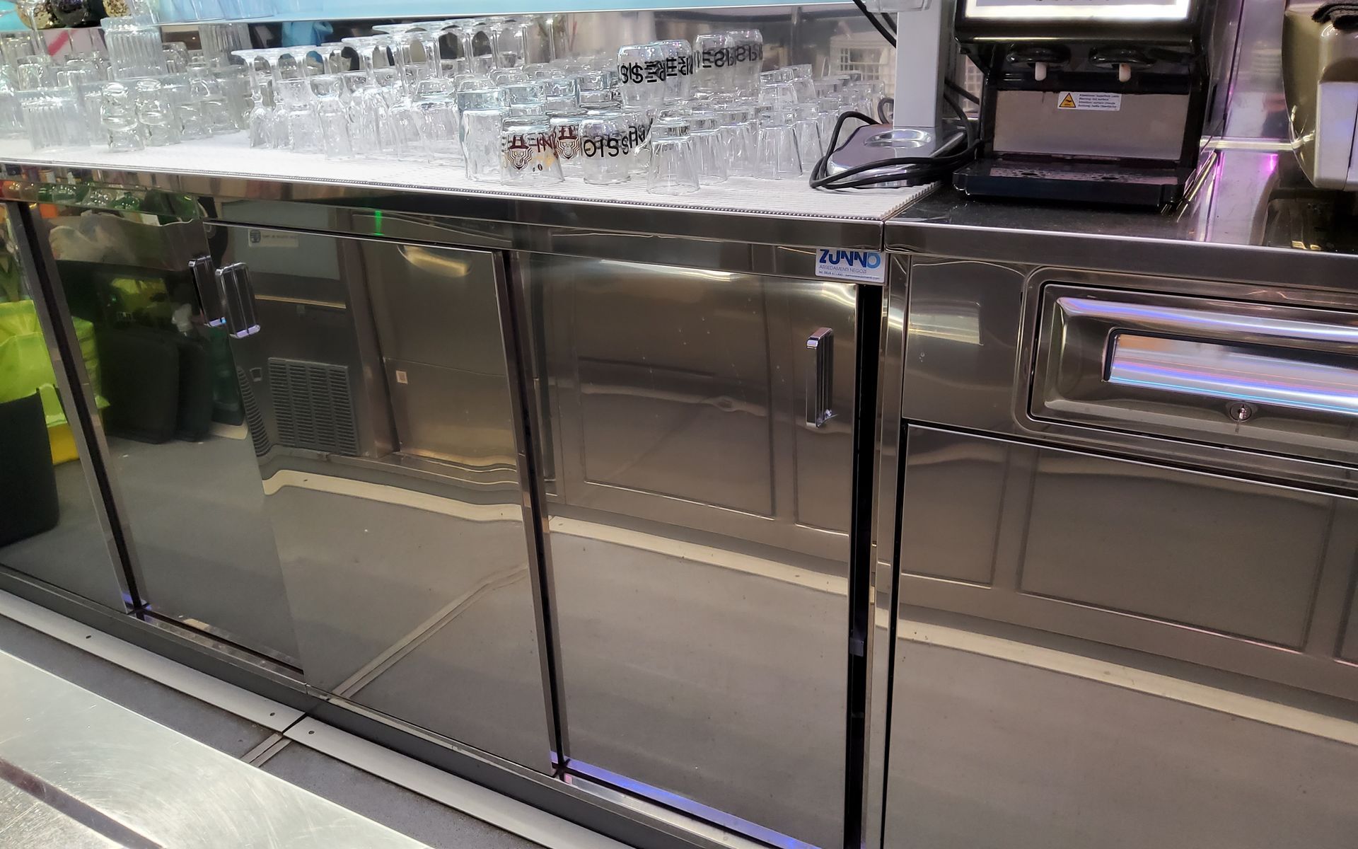 Frigorifero da bar in acciaio inox con bicchieri su ghiaccio e distributore di bevande.