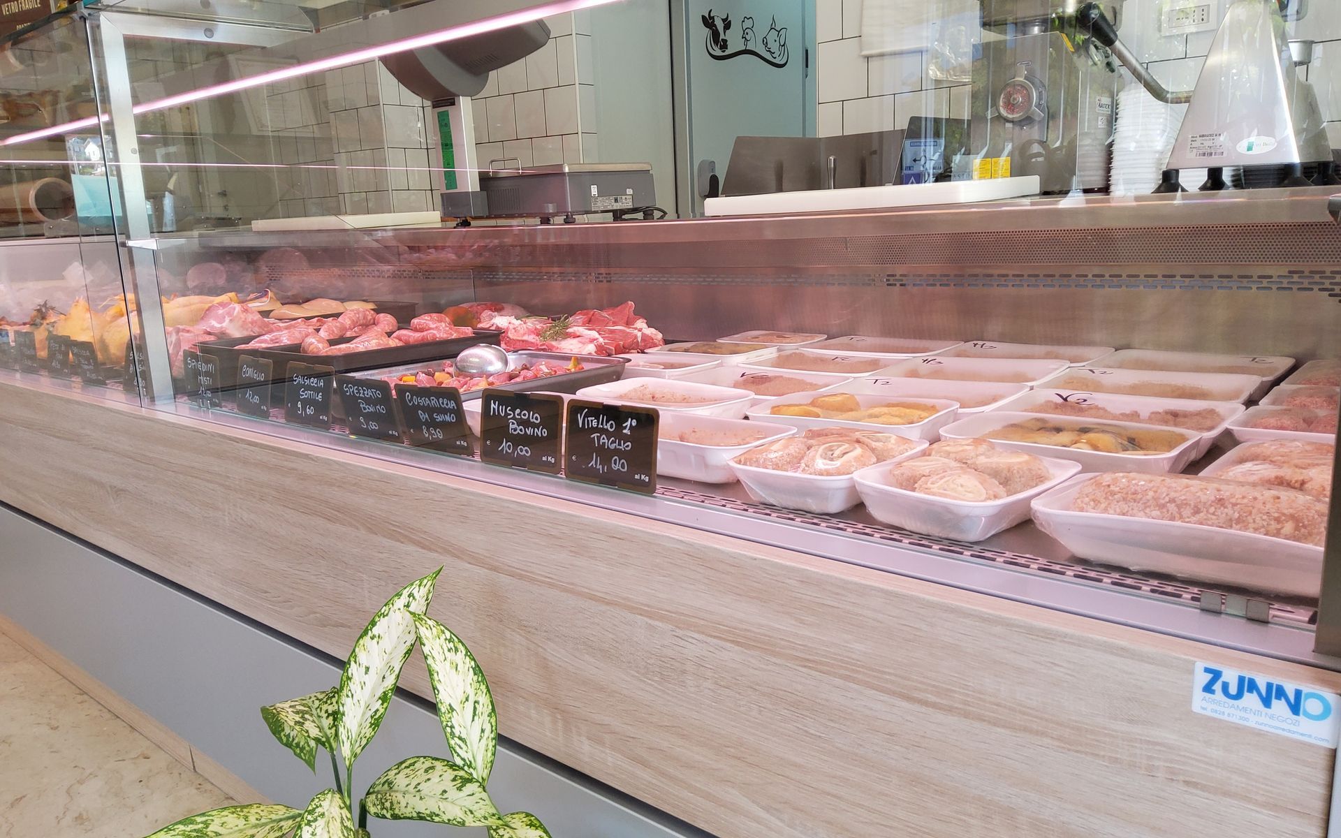 Vetrina espositiva con vari tagli di carne e piatti preparati in un ambiente da negozio.