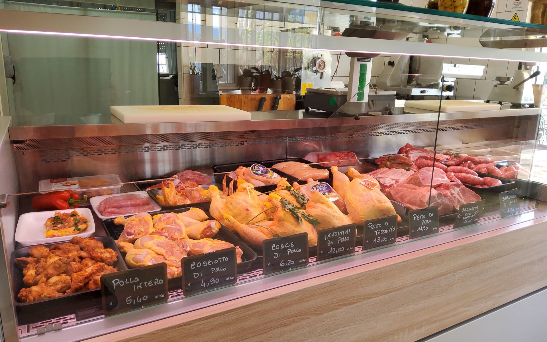 Vetrina di una macelleria con vari tagli di pollo e salsicce.