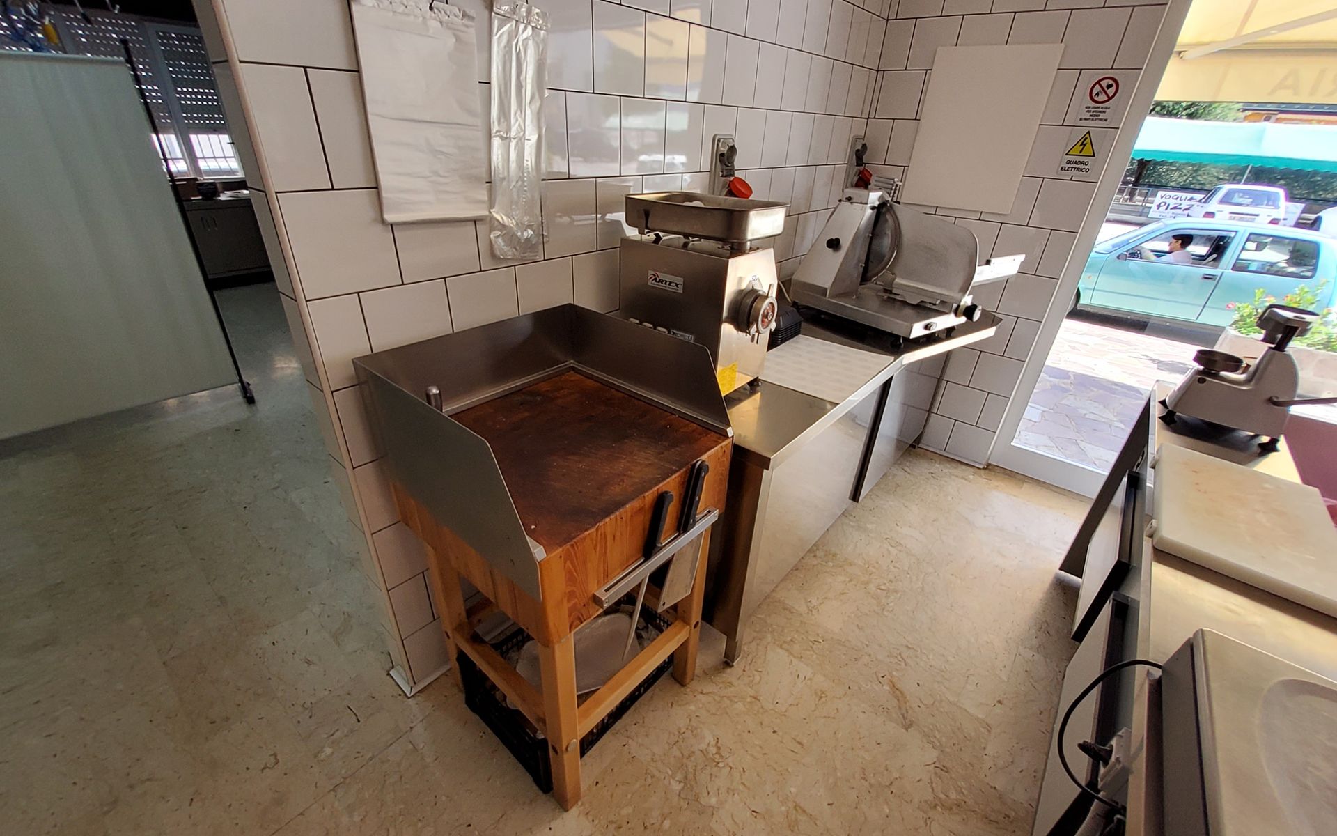 Cucina commerciale con tritacarne, affettatrice e bancone da macellaio.