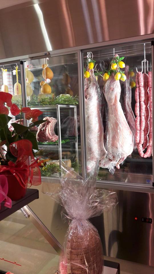 Vetrina con salumi e insaccati appesi, limoni come decorazioni.