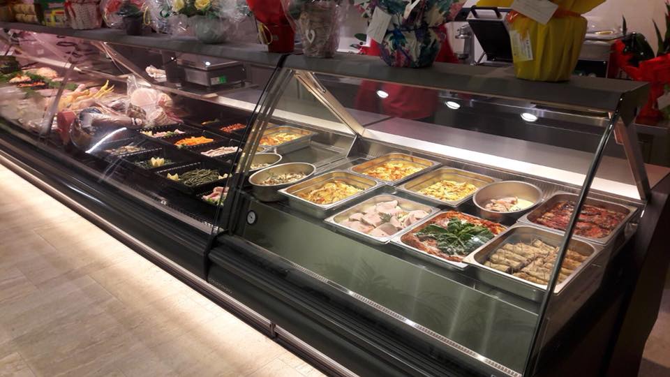 Una vetrina gastronomica piena di vari prodotti alimentari preparati.