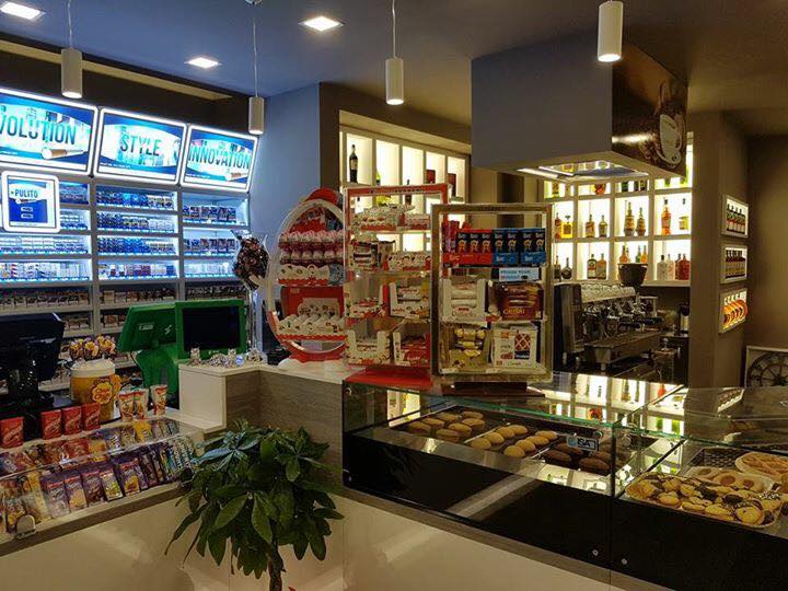 All'interno di un minimarket ben illuminato, con tabacco, snack, caffè e un'esposizione di dolci.
