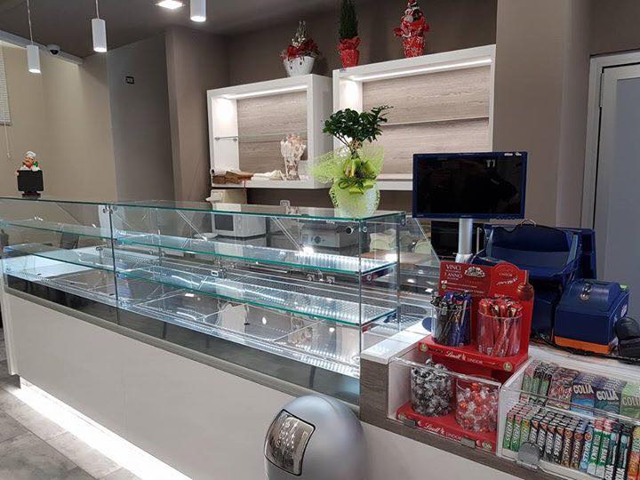 Un bancone da panetteria espone i dolci, con scaffali e un registratore di cassa.
