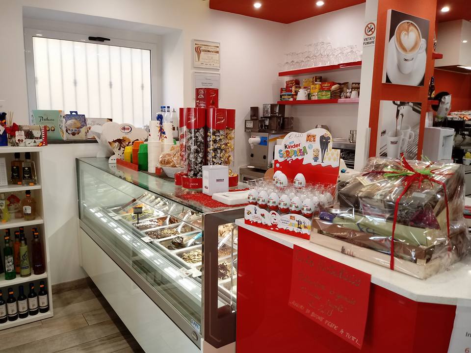 Interno di una gelateria con vetrina di gelato, caramelle e regali confezionati.