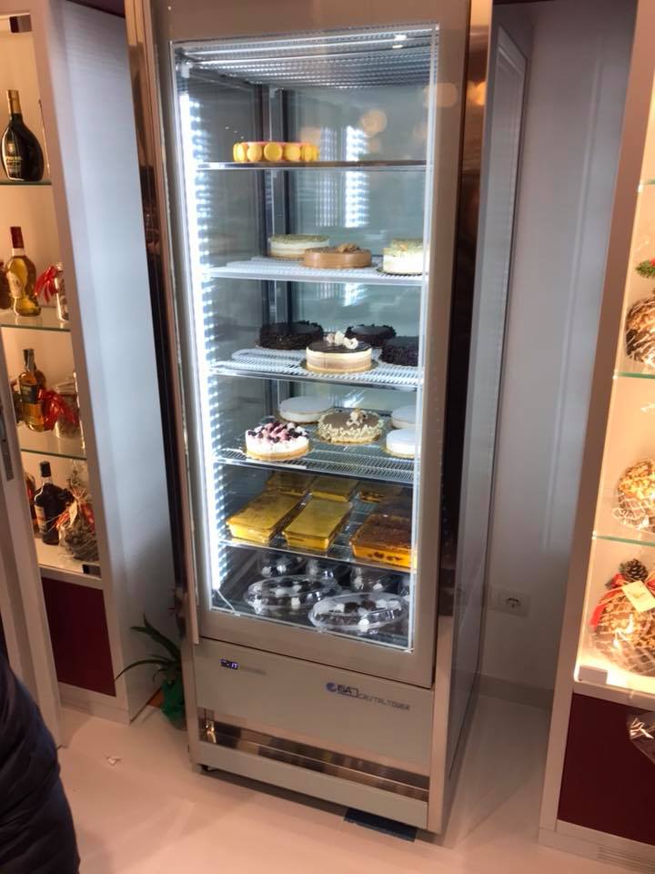 Vetrina refrigerata con vari prodotti da forno: torte, pasticcini e dolcetti. Cornice in argento con ante in vetro.