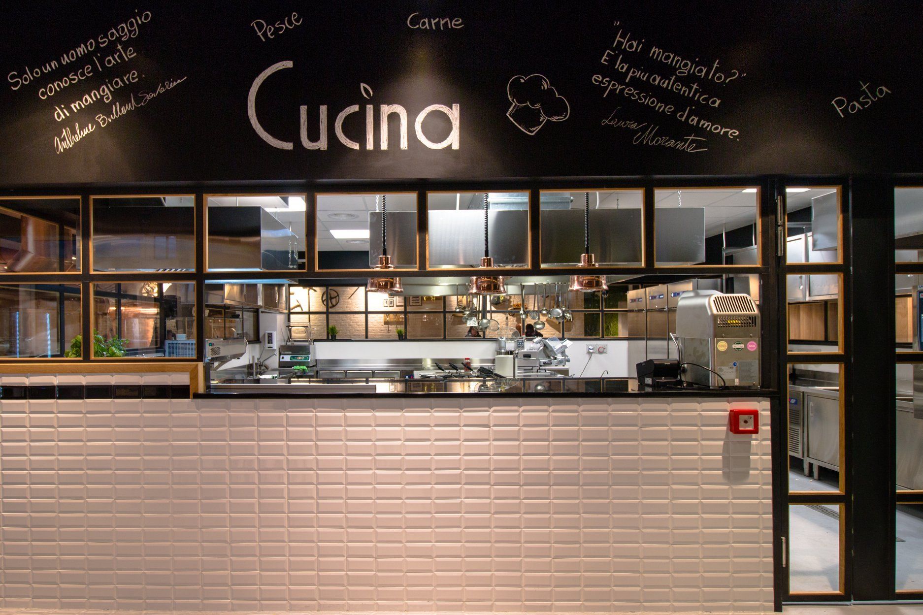 Vetrina del negozio Cucina con insegna nera, piastrelle bianche e interni della cucina visibili.