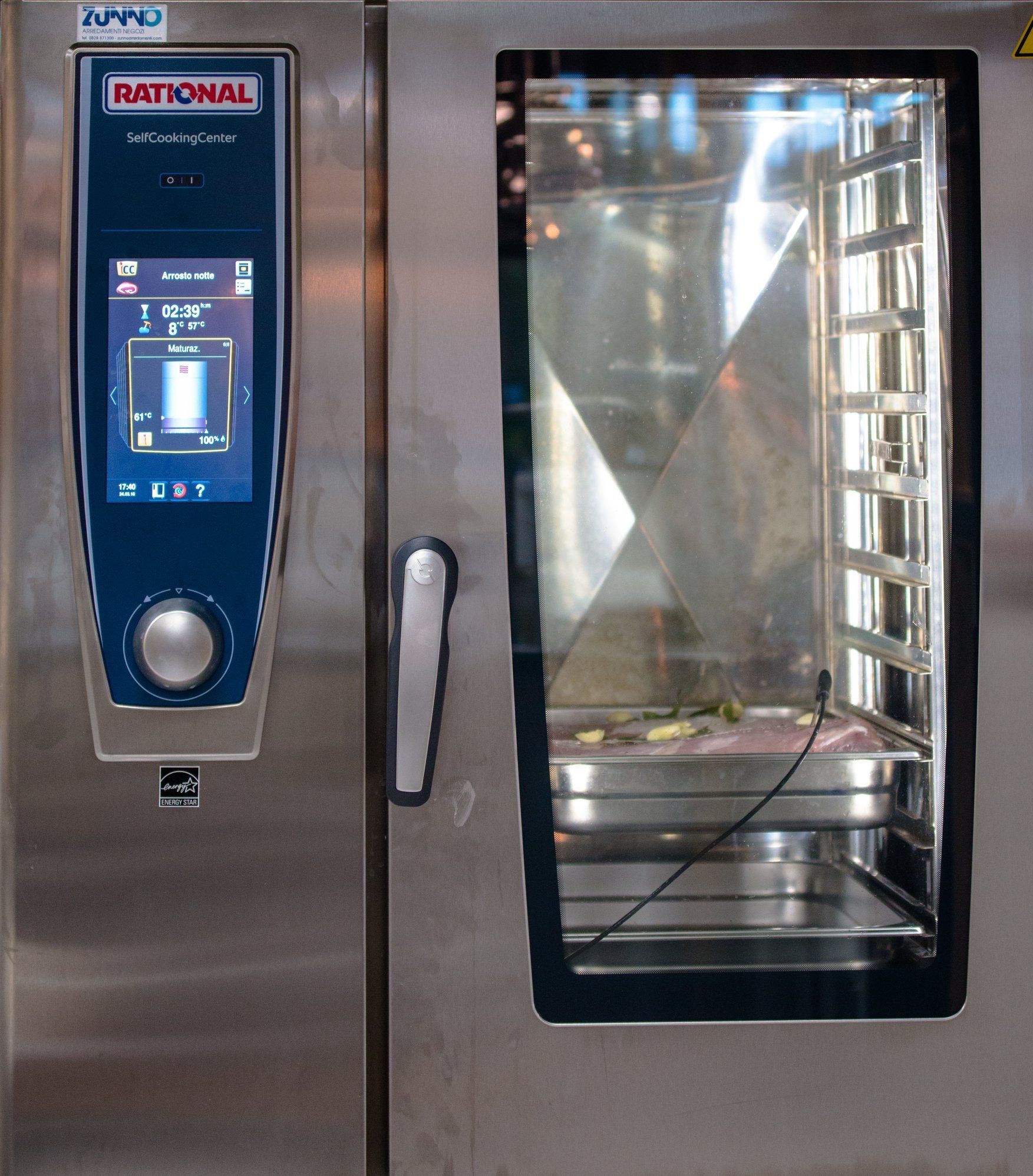Forno combinato Rational in acciaio inox con pannello di controllo touch screen e cibo all'interno.
