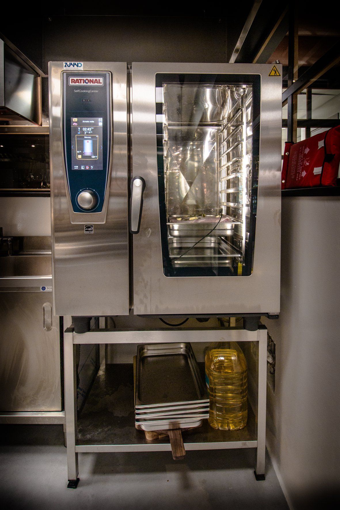 Forno combinato commerciale in acciaio inox su supporto metallico, ambiente cucina.