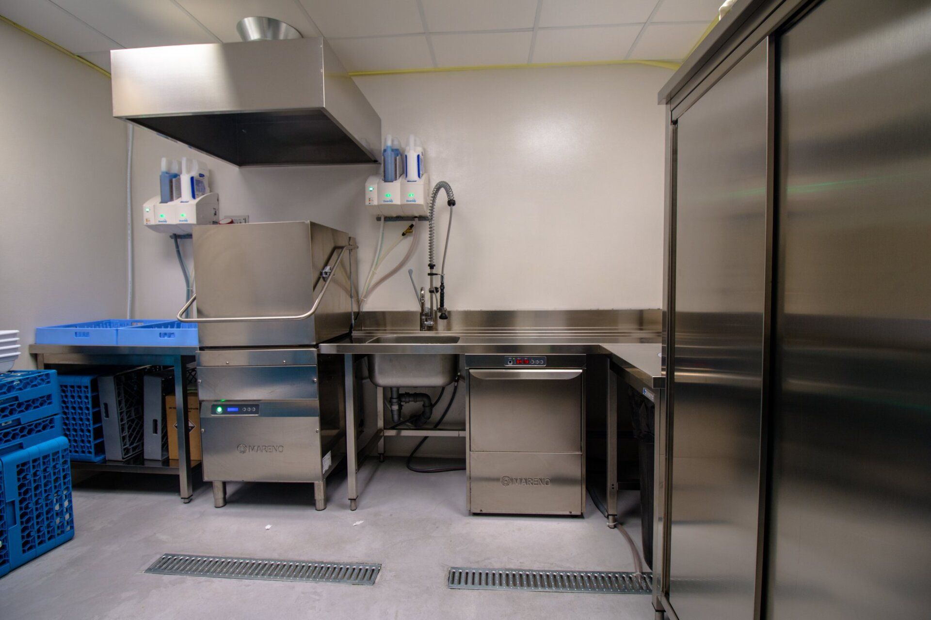 Cucina commerciale in acciaio inox con zona lavaggio stoviglie.